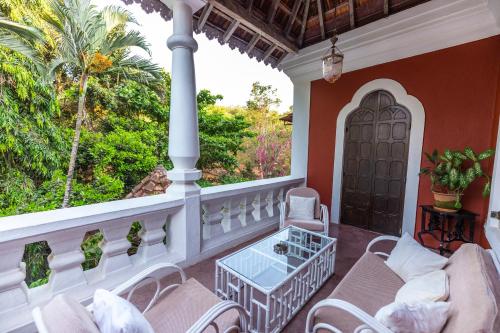a balcony with chairs and a table and a window at Marbella Guest House in Sinquerim