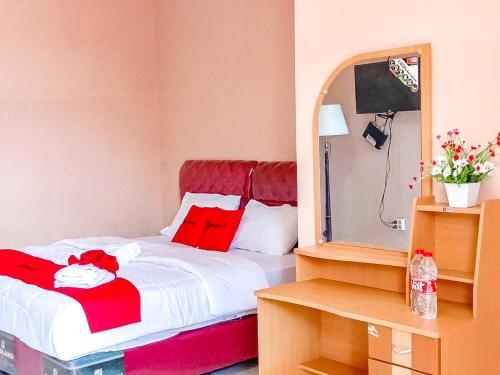 a bedroom with a bed with red pillows and a mirror at RedDoorz near Reremi Pemancar Manokwari in Manokwari
