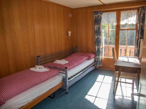 a small room with two beds and a window at Chalet Sturmfang in Adelboden