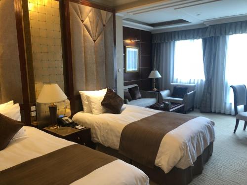 a hotel room with two beds and a chair at Xijiao State Guest Hotel in Shanghai