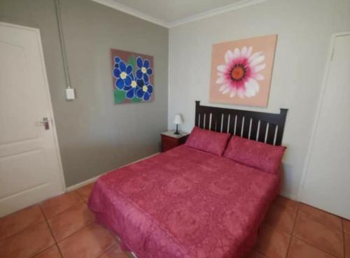 a bedroom with a bed with a red bedspread at N-One Self Catering in Goodwood