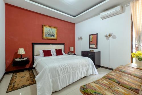 a bedroom with a large bed and a red wall at Buminanienie Guesthouse Bandung in Bandung