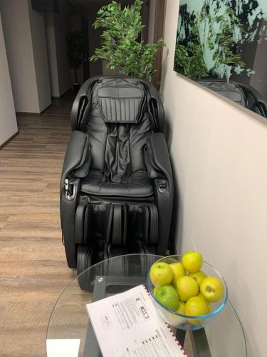 a black chair sitting next to a glass table with a bowl of fruit at Waterfront Lodge in Dunapataj
