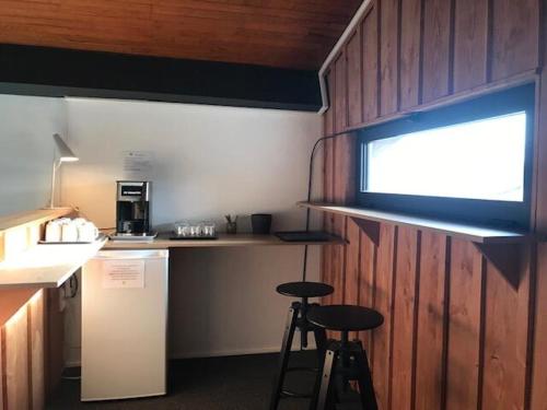 a kitchen with two stools and a counter with a window at Hôtel la petite auberge in Arès