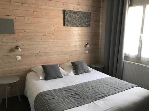 a bedroom with a large bed and a wooden wall at Hôtel la petite auberge in Arès