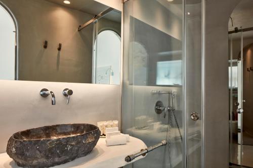 a bathroom with a large stone sink and a shower at Homeric Poems in Fira