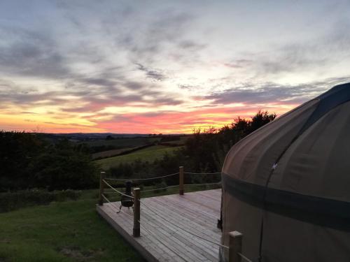 a rv parked on a wooden deck at sunset at Looe Yurts in Looe