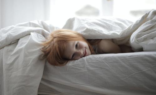 a young girl is laying on a bed at Vakantiewoning Petit Watou in Poperinge
