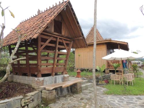 a wooden building with a bench and an umbrella at Singgasana Villa & Resto in Bedakah