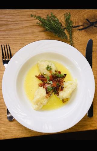 a white plate of food on a wooden table at Weingut Weidlhof - Suite & Breakfast - Vacation for wine lovers in Caldaro