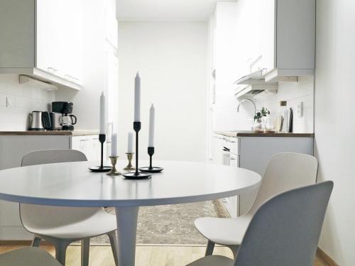 a white dining room with a white table and chairs at 2ndhomes Tampere "Espa" Apartment - New Apt, Sunset View and Own Sauna near City Center & Finlayson Area in Tampere