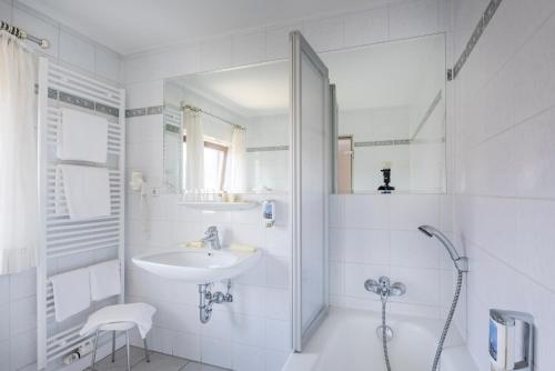 a white bathroom with a sink and a shower at Gasthof Neuwirt in Ismaning