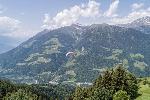 a red parachute is flying over a mountain valley at Mountain Lodge Prennanger in Schenna