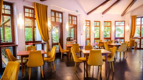a restaurant with tables and chairs and windows at Hotel Villa Baltica in Sopot