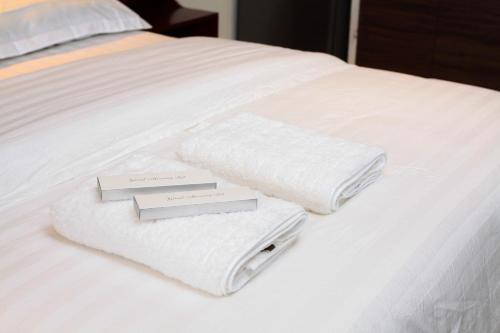 two towels sitting on top of a white bed at Malate Bayview Mansion city view in Manila