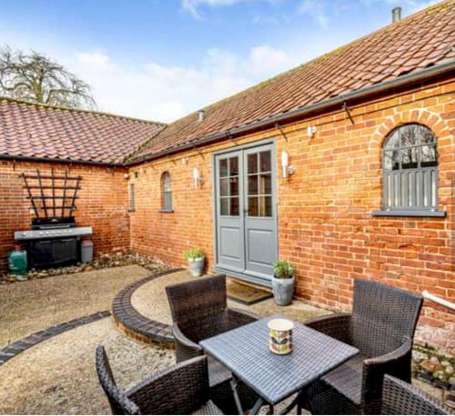 a patio with a table and chairs and a brick building at Chestnut Lodge in East Dereham