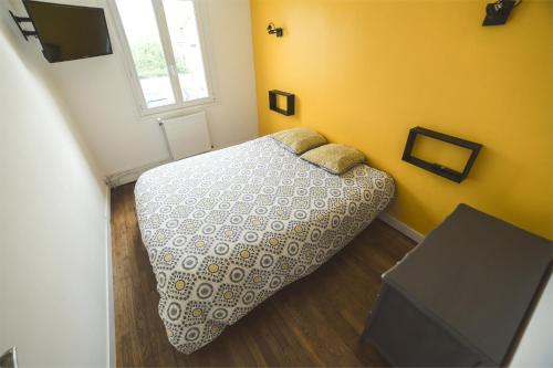 um quarto com uma cama numa parede amarela em "LOUJADE" Maison 3 Chambres à Moncé en Belin - Proche Circuit 24h du Mans em Moncé-en-Belin