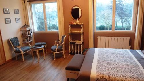 a bedroom with a bed and a mirror and chairs at Rêve d'Authie in Dompierre-sur-Authie