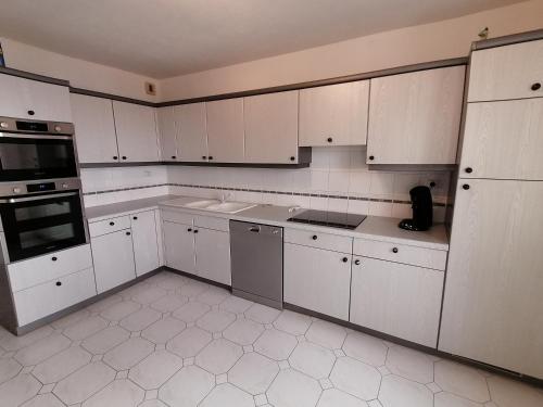 une cuisine blanche avec des armoires et des appareils blancs dans l'établissement Appartement triangle d'or Saint Raphaël, à Saint-Raphaël