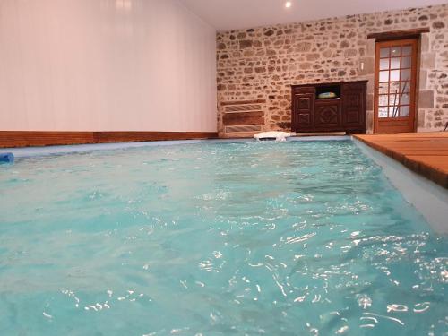 a large swimming pool with blue water in a room at Auverg'Nature Chambre Auvergnate massage ayurvédique in Espinasse