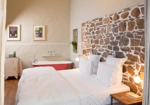 a bedroom with a large bed and a stone wall at La Grenadine in Cape Town