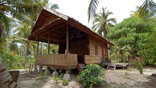 una pequeña cabaña de madera con un banco delante en Erens Guest House en Waisai