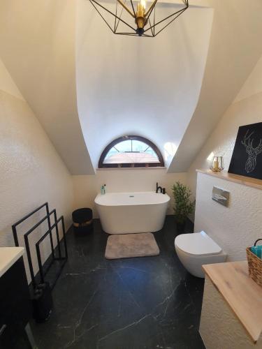 a bathroom with a white tub and a toilet at Mazurska Osada nad jeziorem Orzysz in Skomack Wielki