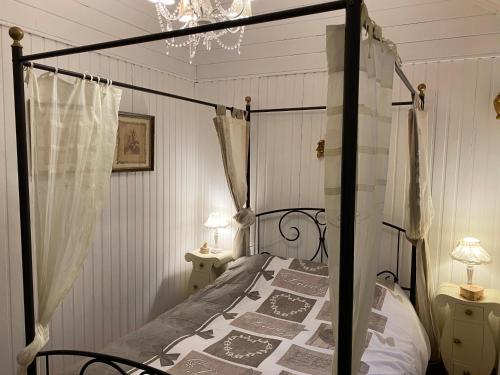 ロシュオーにあるLe Cap Vertのベッドルーム1室(黒い天蓋付きベッド1台、テーブル2台付)