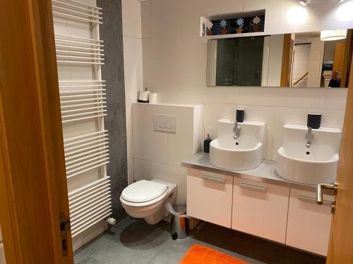 een badkamer met 2 wastafels en een toilet bij Le Cap Vert in Rochehaut