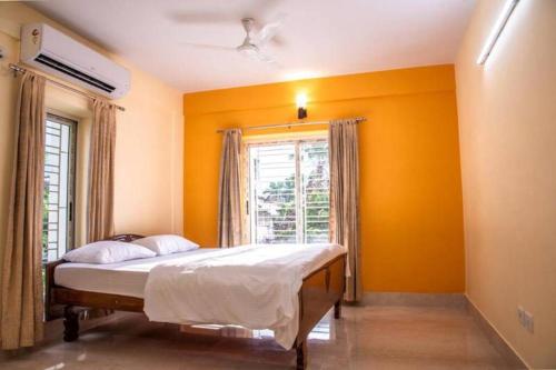 a bedroom with a bed with yellow walls and a window at Diamond By Olys Apartment in Kolkata