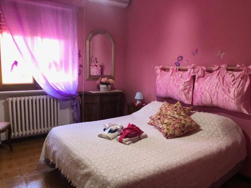 a pink bedroom with a bed with a stuffed animal on it at B&b ANNA in Bolsena
