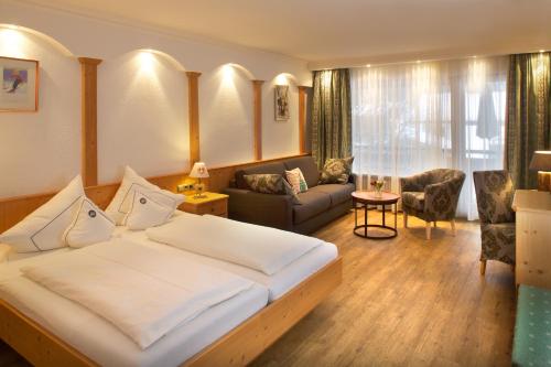 a bedroom with a large bed and a living room at Hotel Menning ***S in Oberstdorf