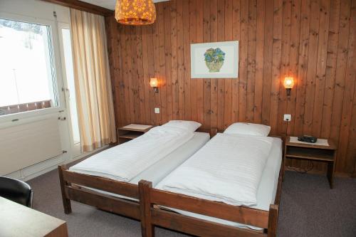 two beds in a room with wooden walls and a window at Hotel Sporting in Marbach