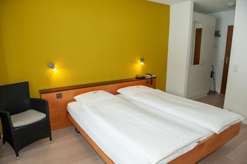a bed in a room with a yellow wall at Hotel Sporting in Marbach