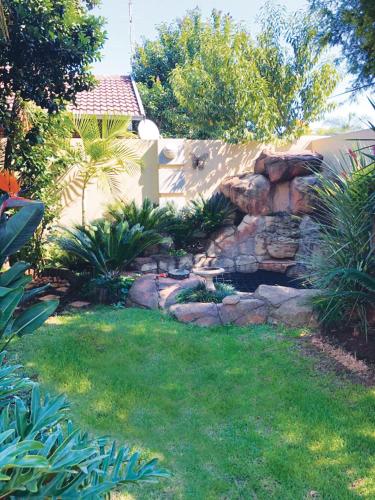a backyard with a stone wall and a yard at African BnB - The Boutique Experience in Benoni