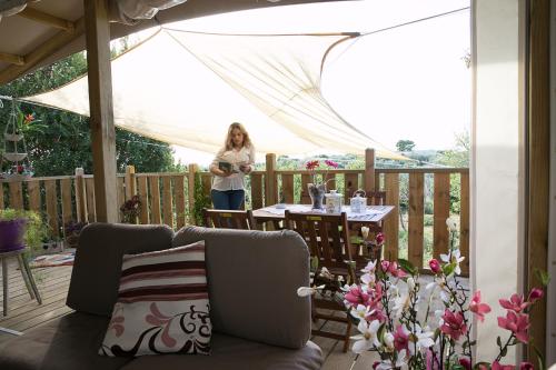 a woman standing on a deck with a table at Ciriga Sicily Glamping in Santa Maria Del Focallo
