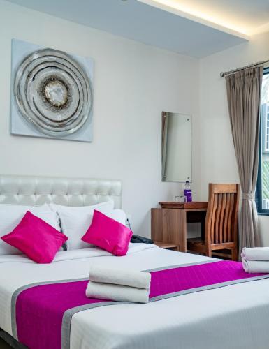 a bedroom with a large bed with pink pillows at Nexstay Treats Inn in Kozhikode
