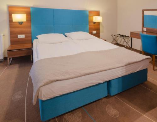 duże łóżko z niebieskim zagłówkiem w pokoju w obiekcie Holiday Home Aparthotel w mieście Międzyzdroje