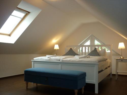 Pension Dachgeschosswohnung في Bastorf: غرفة نوم مع سرير أبيض مع مسند أزرق