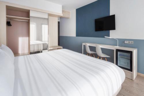 a bedroom with a large white bed and a tv at B&B HOTEL Donostia Aeropuerto in Oiartzun