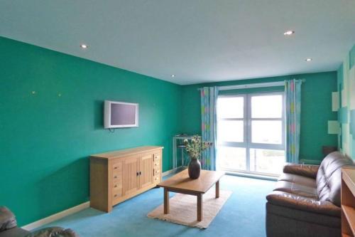 a living room with green walls and a couch and a table at Comfortable, self contained 2 double beds town apartment near Pittodrie Stadium in Aberdeen