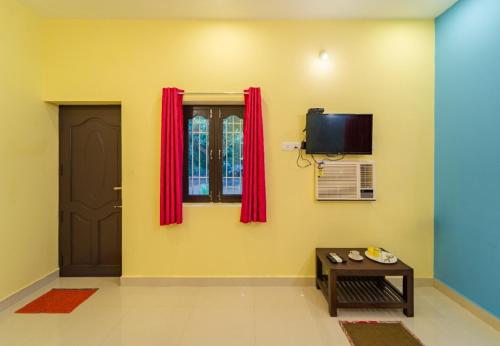 Aashikha Farm House في بونديتْشيري: غرفة مع باب ونافذة مع ستائر حمراء