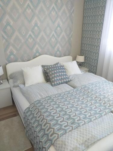 a bedroom with a large bed with blue and gray sheets at Elizabeth Apartman 2 in Hévíz