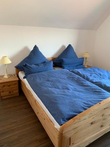 Schlafzimmer mit einem Holzbett mit blauer Bettwäsche und Kissen in der Unterkunft Ferienwohnung_25 in Uphusum