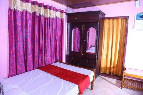 a bedroom with a bed and a dresser and curtains at Eden Homestay Idukki in Idukki