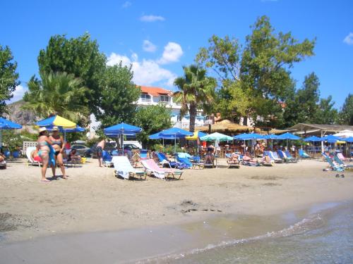 a group of people sitting on a beach with umbrellas at Hercules Sea Front Studios in Katelios