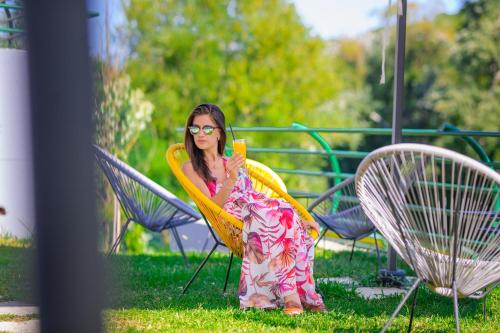 a woman sitting in a chair holding a cell phone at Hotel RIO VERDE in Podgorica