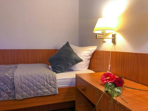 a bedroom with a bed and a table with a lamp at Hotel Kaiser in Mönchengladbach