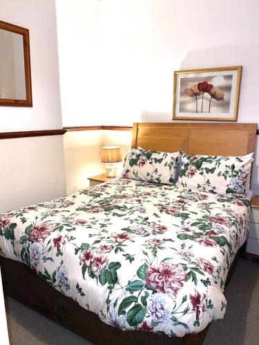 a bedroom with a bed with a floral bedspread at Seaford Lodge Apartments in Weston-super-Mare