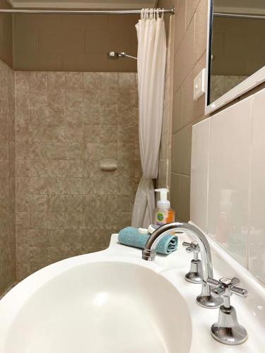 a bathroom with a white sink and a mirror at Apollo Motel Parkes in Parkes